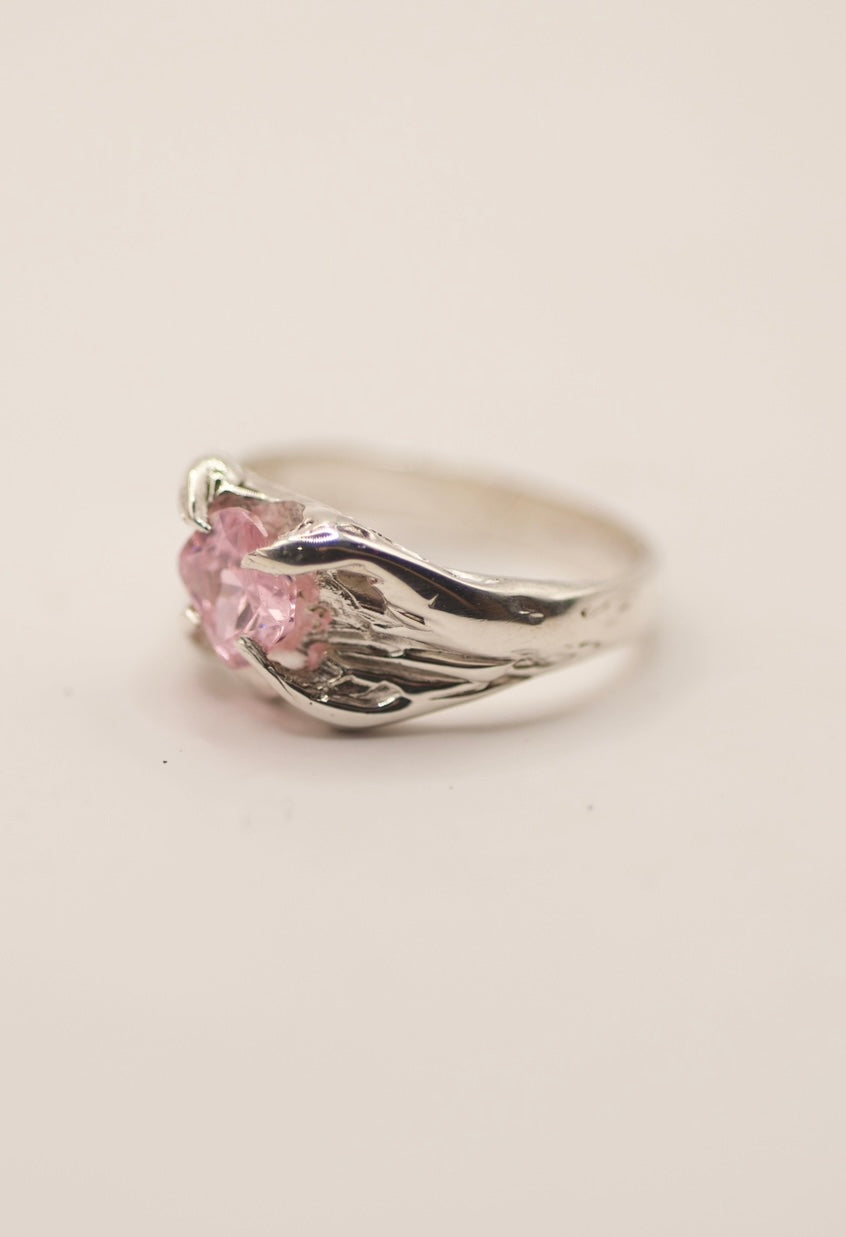 Close-up of a gothic alternative silver ring featuring a cushion-cut light pink cubic zirconia, secured by four molten organic claws, showcasing the artistry of lost wax sculpting