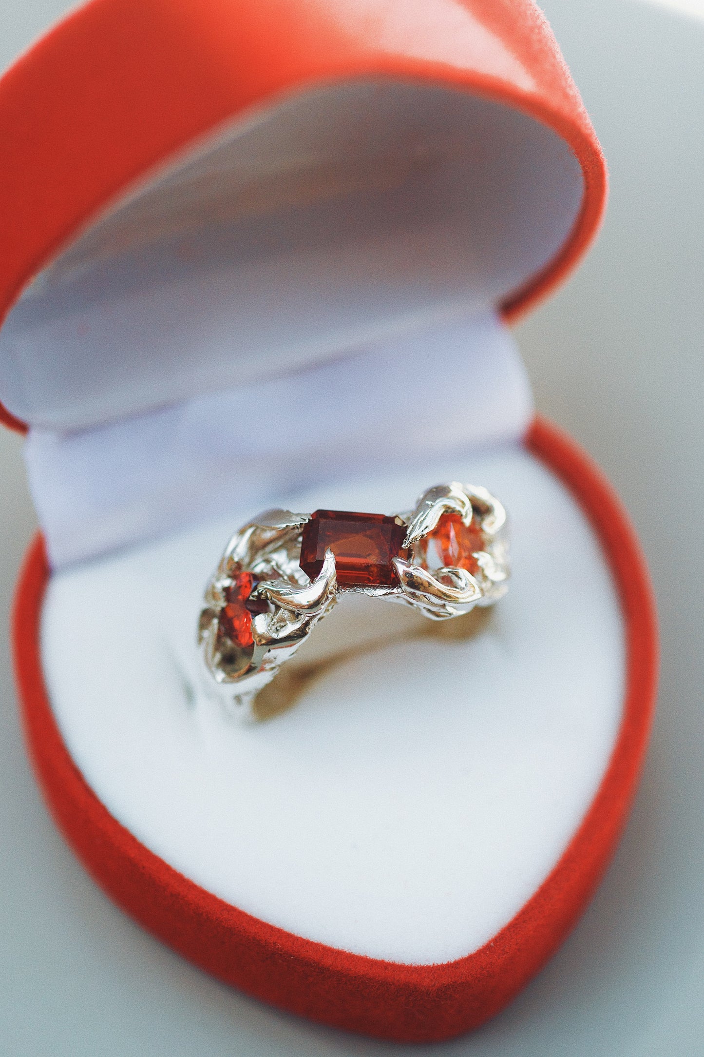 A romantic gothic ring showcasing two ruby hearts and a lab-grown nano crystal, held by imperfect claws, with a molten metal band and intricate detailing. Hand-carved on the Sunshine Coast, Australia.